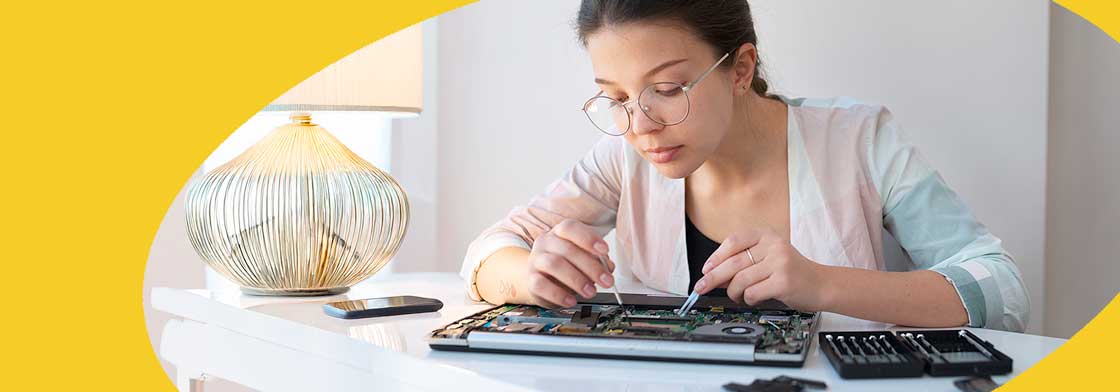 Headerbild für den Support. Eine junge Frau die an einem geöffneten Notebook arbeitet. Links von ihr liegt ein Handy und es steht eine Lampe daneben.